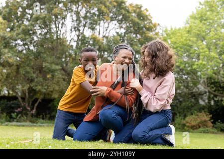 Die Familie lacht gemeinsam im Freien und genießt spielerische Momente auf grünem Gras Stockfoto