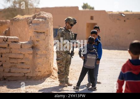 Syrien. Oktober 2024. Ein Soldat der US-Armee aus der Charlie Company, 1. Bataillon, 181. Infanterieregiment, 44. Infanterie-Brigade-Kampfteam, das der Combined Joint Task Force - Operation Inhärent Resolve zugeordnet ist, gibt lokalen Kindern während einer abgehängten Patrouille durch ein Dorf im Nordosten Syriens Süßigkeiten. (Kreditbild: © Emma Scearce/USA Army/ZUMA Press Wire) NUR REDAKTIONELLE VERWENDUNG! Nicht für kommerzielle ZWECKE! Stockfoto