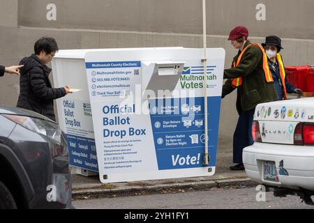 Wähler und Wählermeldebeamte an einer Wahlurne auf dem Bürgersteig vor der Wahlabteilung des Multnomah County in Portland am... Stockfoto