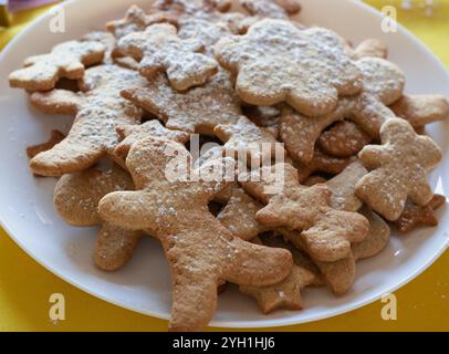 Weihnachtskekse auf weißem Teller. Knusprige Lebkuchenkekse mit Puderzucker. Weihnachtshintergrund. Neujahrsvergnügen. Zimtgebäck aus nächster Nähe. Stockfoto