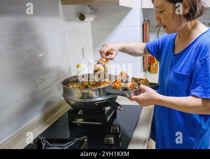 Frau kocht haarige Krabben in einem Topf. Köstliche Yangcheng-Seekrebse für ein Familienessen. Stockfoto