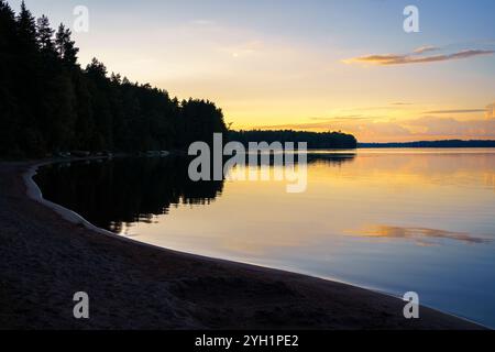 Ruhiges Seeufer mit Sandstrand bei Sonnenuntergang Stockfoto