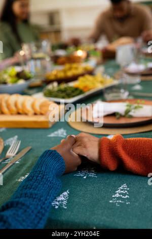 Weihnachtszeit, multirassische Familie hält Hände an festlichem Esstisch, zu Hause Stockfoto