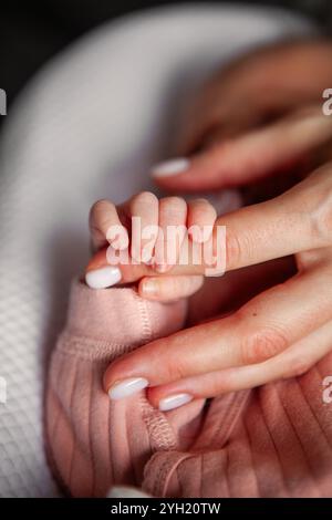 Nahaufnahme der Hand des Neugeborenen, die den Mutterfinger zärtlich greift, herzerwärmender Moment der Verbindung und Liebe zwischen Mutter und Kind Stockfoto