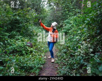 Glückliche Wanderer mit Smartphone beim Wandern auf einem Hügel an einem regnerischen Tag. Stockfoto