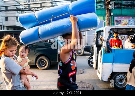 Ein philippinischer Marktarbeiter trägt seine Waren auf einem Markt in China Town, Binondo District, Manila, den Philippinen. Stockfoto