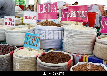 Samarkand, Usbekistan - 6. Juli 2024: Reis und Hülsenfrüchte zum Verkauf auf dem Samarkand Markt mit Schildern mit kyrillischen Zeichen Stockfoto