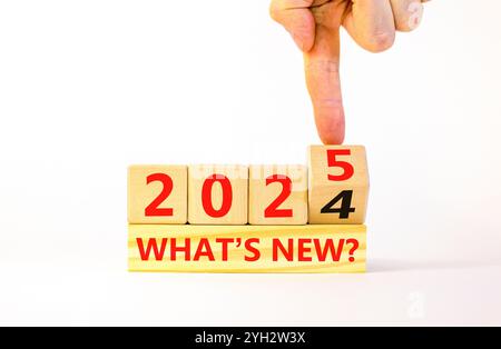 2023 Was ist das neue Symbol? Concept Words Was ist neu 2024 bis 2025 auf schönen Holzblöcken? Geschäftsmann Hand. Schöner weißer Tisch weißer Hintergrund, Stockfoto