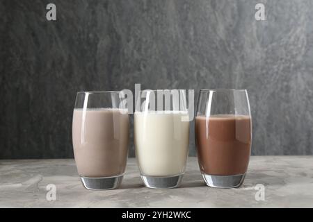 Köstliche Proteinshakes in Gläsern auf grauem, strukturiertem Tisch Stockfoto