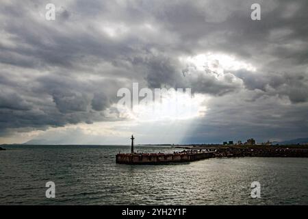 Lichtstrahlen brechen durch stürmische Wolken über dem Hafen Stockfoto