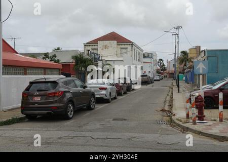 Farbenfrohe Gebäude im Kolonialstil in der Nähe des Stadtzentrums mit schmalen Straßen, Palmen und einigen geparkten Autos in Oranjestad auf Aruba. Stockfoto