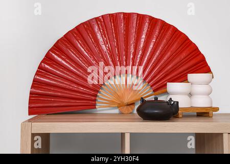 Holzschrank mit rotem Ventilator und Teekanne im Wohnzimmer. Chinesisches Neujahrsfest Stockfoto