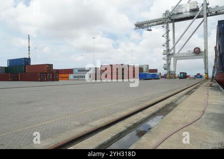 Kleiner Containerterminal mit verstauten Containern verschiedener Verlader, Portalkran und Fahrzeugträger in Oranjestad, Karibikinsel Aruba. Stockfoto