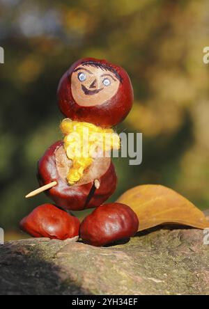 Kastanienfigur mit gelbem Schal und Blättern auf Baumstamm, Nordrhein-Westfalen, Deutschland, Europa Stockfoto