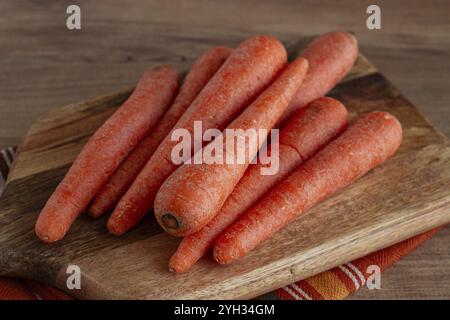Frische Karotten auf einem Schneidebrett, Holztisch, rohe Karotten, keine Leute Stockfoto