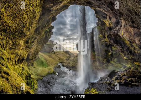 Blick hinter den Kvernufoss-Wasserfall in Island mit einem versteckten Juwel mit üppigem grünem Moos, zerklüfteten Felsformationen und einem kaskadierenden Wasserfall Stockfoto