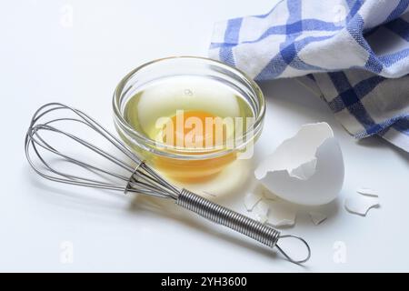 Eiweiß und Eigelb in Glasschale und Eierschalen, Schneebesen Stockfoto