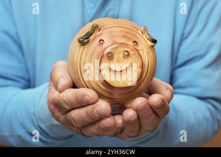 Senior holding Sparschwein in der Hand Stockfoto