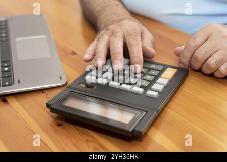 Mann, der Rechner benutzt, Rechnungen zu Hause berechnet Stockfoto