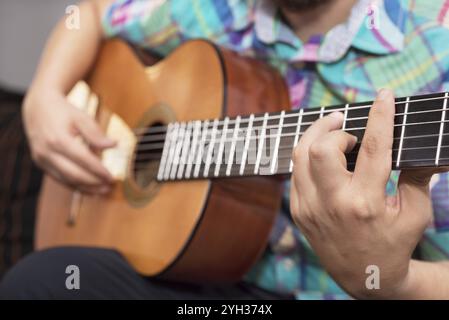 Bärtiger Hipster-Mann, der Akustikgitarre spielt. Nahaufnahme selektiver Fokus auf Hand Stockfoto