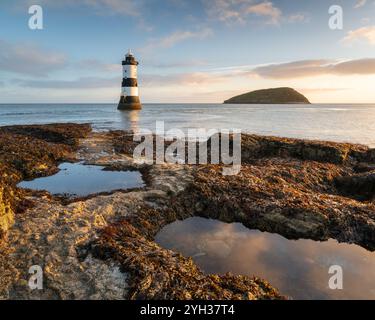 An einem ruhigen und kühlen Morgen Mitte Oktober leuchtet das wunderschöne goldene Morgenlicht über dem Trwyn du Lighthouse am Penmon Point auf Anglesey. Stockfoto