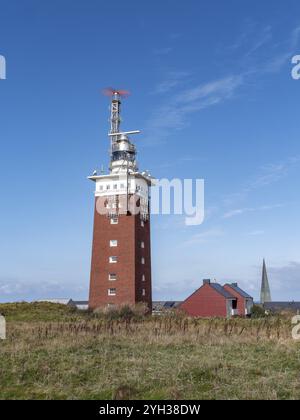 Leuchtturm von Helgoland mit Radarantenne auf dem hügeligen Oberland der Hochseeinsel Helgoland und Backsteinbau und Turm der Nicolaikirche Stockfoto