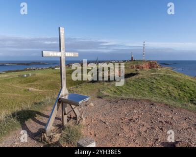 Gipfelkreuz des Pinnebergs auf dem höchsten Punkt der Insel (61, 3 m) und im Hintergrund hügeliges Oberland, Leuchtturm von Helgoland und in den Stockfoto