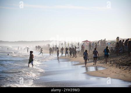 Punta del Diablo, Rocha, Uruguay. Februar 2022: Menschenmassen genießen einen sonnigen Tag am Strand mit Wellen und Sonnenschirmen. Stockfoto