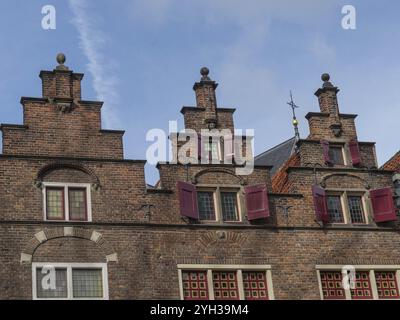 Historische Gebäude mit markanten Ziegelgiebeln und roten Rollläden unter blauem Himmel, nijmegen, gelderland, niederlande Stockfoto