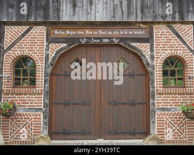 Großes Holztor in einer Backsteinmauer mit dekorativen Blumen an den Seiten, Marbeck, westfalen, deutschland Stockfoto