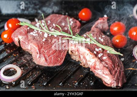 Saftiges Fleisch, das Steak wird mit Kirschtomaten, Rosmarin und grobem Meersalz gegrillt. Hochwertige Fotos Stockfoto