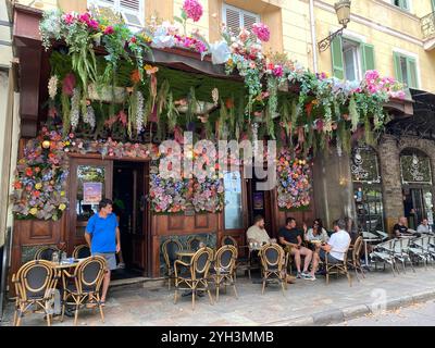 Bezauberndes Café mit farbenfrohen Blumendekorationen und Sitzplätzen im Freien Stockfoto