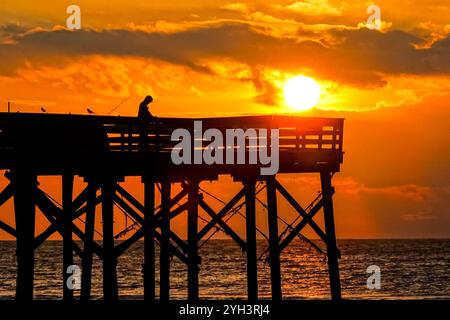 Isle Of Palms, Usa. November 2024. Ein einsamer Fischer, der vom Sonnenaufgang umrahmt wird, steht am Angelpier der Isle of Palms, während die Sonne am 9. November 2024 in Isle of Palms, South Carolina, durch die Morgenwolken über dem Atlantik bricht. Sonniges Wetter in den 70er Jahren wird für das niedere Land für die nächsten zehn Tage prognostiziert. Quelle: Richard Ellis/Richard Ellis/Alamy Live News Stockfoto