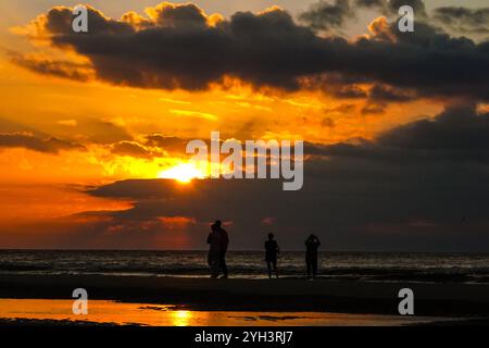 Isle Of Palms, Usa. November 2024. Touristen, die von Sonnenaufgang umgeben sind, stehen bei Ebbe auf einer Sandbank und beobachten den Sonnenaufgang über dem Atlantikhorizont am Front Beach, 9. November 2024 in Isle of Palms, South Carolina. Sonniges Wetter in den 70er Jahren wird für das niedere Land für die nächsten zehn Tage prognostiziert. Quelle: Richard Ellis/Richard Ellis/Alamy Live News Stockfoto