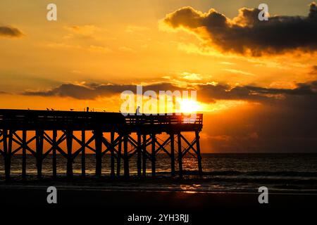 Isle Of Palms, Usa. November 2024. Ein einsamer Fischer, der vom Sonnenaufgang umrahmt wird, steht am Angelpier der Isle of Palms, während die Sonne am 9. November 2024 in Isle of Palms, South Carolina, durch die Morgenwolken über dem Atlantik bricht. Sonniges Wetter in den 70er Jahren wird für das niedere Land für die nächsten zehn Tage prognostiziert. Quelle: Richard Ellis/Richard Ellis/Alamy Live News Stockfoto