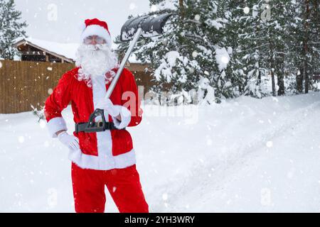 Der Weihnachtsmann reinigt im Winter draußen nach einem Schneefall Schnee mit Schaufel. Die Straßen im Dorf zu reinigen, die Passage für Autos freizumachen, schwierig Stockfoto