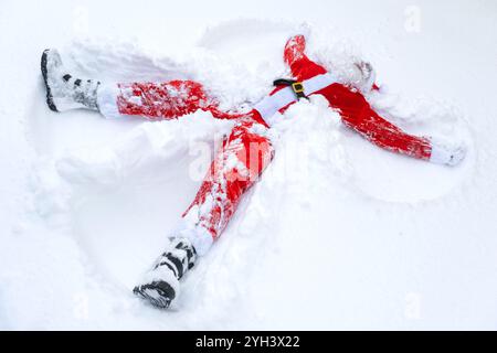 Der Weihnachtsmann macht Schneeengel im Schnee. Humor, Winterspaß, Weihnachtsmann ist müde und betrunken Stockfoto