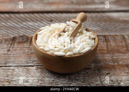 Puffreis in Schüssel und Schaufel auf Holztisch, Nahaufnahme Stockfoto