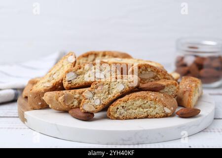 Leckere Mandelkekse (Cantuccini) und Nüsse auf weißem Holztisch, Nahaufnahme Stockfoto