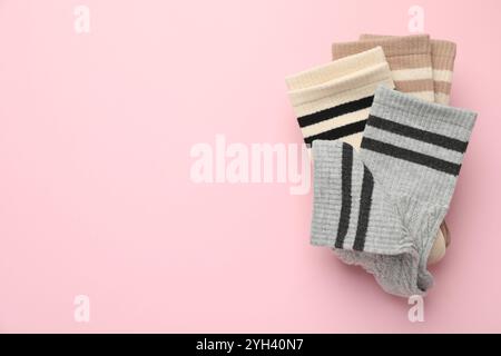 Verschiedene bequeme Socken auf hellrosa Hintergrund, Draufsicht. Leerzeichen für Text Stockfoto