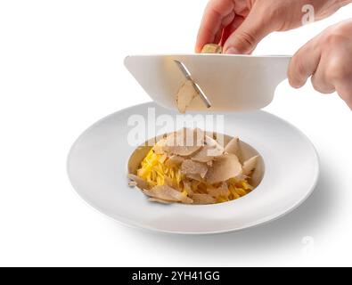 Servieren Sie die weißen Trüffel aus Alba in Italien mit einem Edelstahlschneider auf einem Teller Tagliolini-Spaghetti mit Ei in weißer Platte isoliert auf weiß Stockfoto