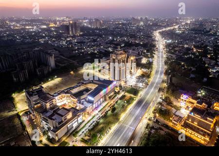 Drohnenaufnahme in der Dämmerung fliegt rückwärts in der Airia Mall mit der mumbai pune Schnellstraße in der Ferne und Gebäuden in der Ferne Stockfoto