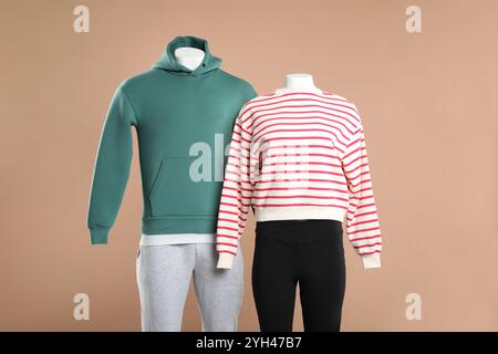 Weibliche und männliche Schaufensterpuppen mit stilvollen Outfits auf beigefarbenem Hintergrund Stockfoto