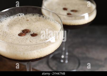 Gläser mit köstlichem Espresso Martini und Kaffeebohnen auf dem Tisch, Nahaufnahme Stockfoto