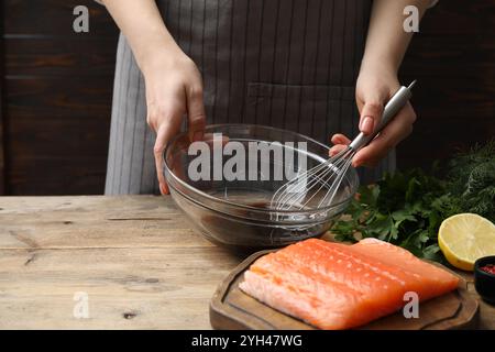 Frau, die Sojamarinade für Lachsfilet am Holztisch macht, Nahaufnahme Stockfoto