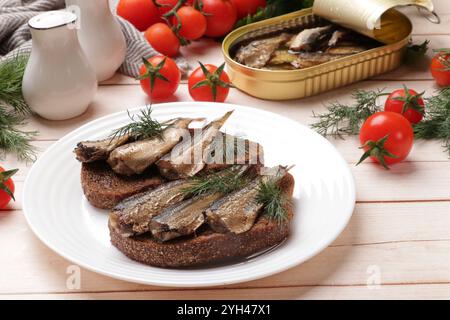 Köstliche Sandwiches mit Sprotten und Dill, serviert auf weißem Holztisch, Nahaufnahme Stockfoto