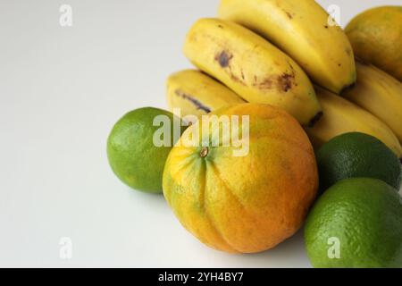 Bananen, Limetten und Orangen auf weißem Hintergrund. Gesunde frische brasilianische tropische Früchte für die mediterrane Ernährung. Konzept der nachhaltigen Landwirtschaft. Stockfoto