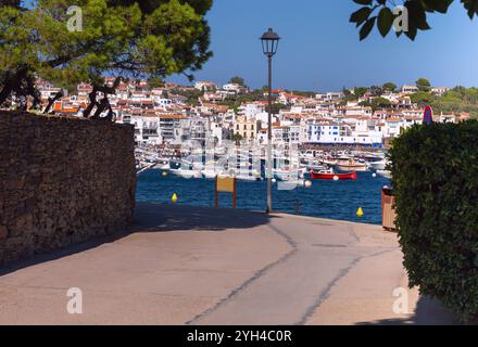 Malerische Aussicht auf den Hafen in Cadaques mit weiß getünchten Gebäuden am Hügel, traditionellen Fischerbooten auf dem Wasser und klarem blauen Himmel, Spai Stockfoto