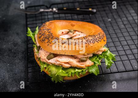 Bagel-Sandwich mit Lochs, Räucherlachs, Salat und Frischkäse auf einem Rack. Schwarzer Hintergrund. Draufsicht. Stockfoto