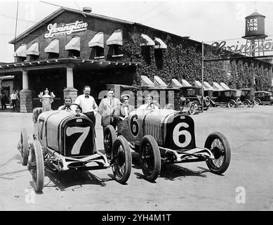 Blick auf zwei Rennwagen und Fahrer (einer mit Trophäe) vor dem Bürogebäude von Lexington Motor Co, Vintage Lexington Motor Company Rennwagen, Fayette County, IN, um 1920. Foto des American Automobile Archive. Stockfoto